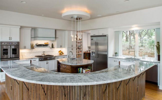 Большая кухня с полукруглым островом и столешницей мрамор